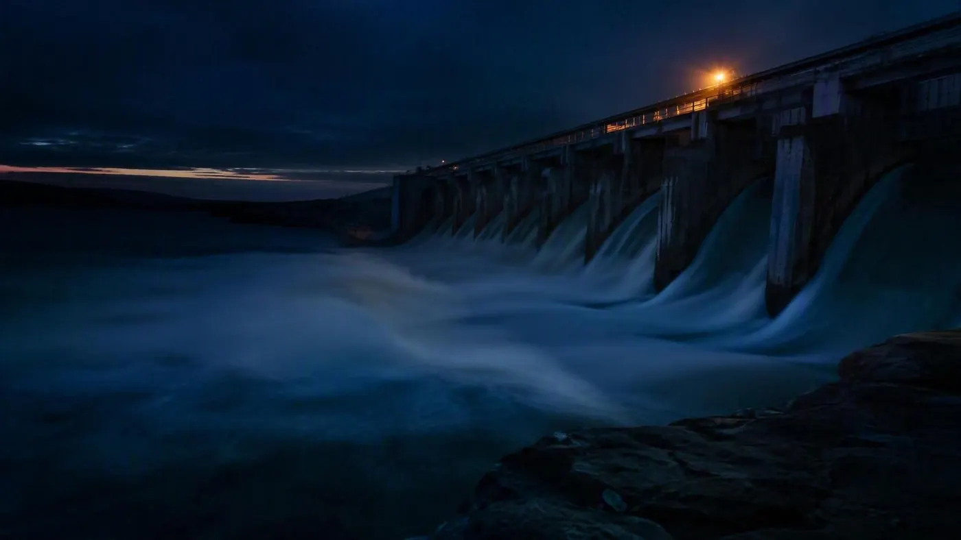 Vertedouro de barragem com água em queda durante a hora azul